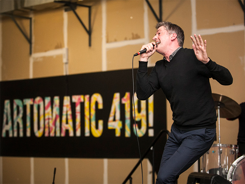 artomatic 4194×3 event image a man singing on stage with an "artomatic 419" sign in the background